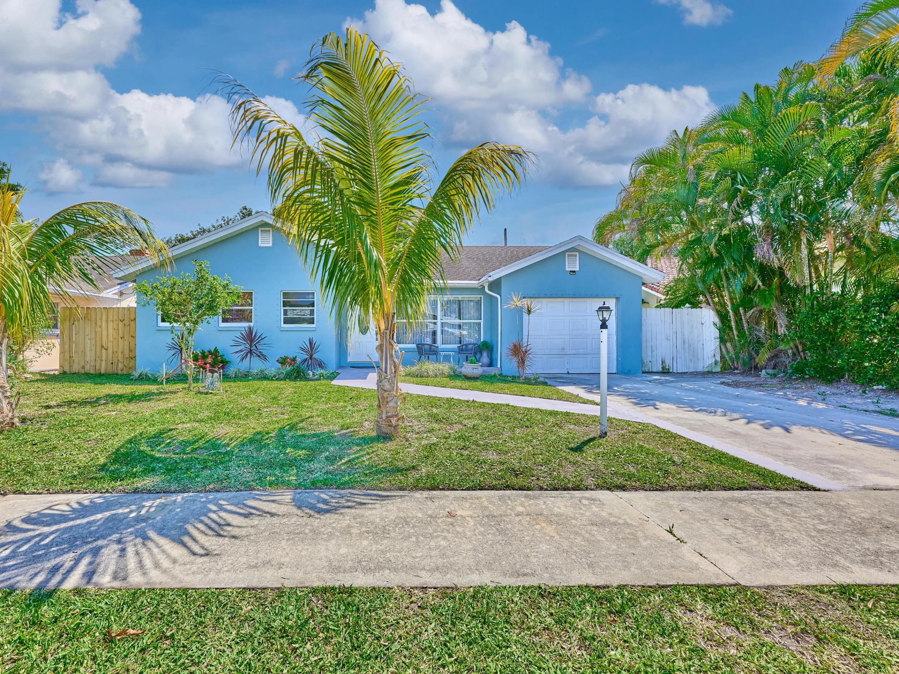 Front exterior with blue siding, a white garage door, and a concrete driveway
