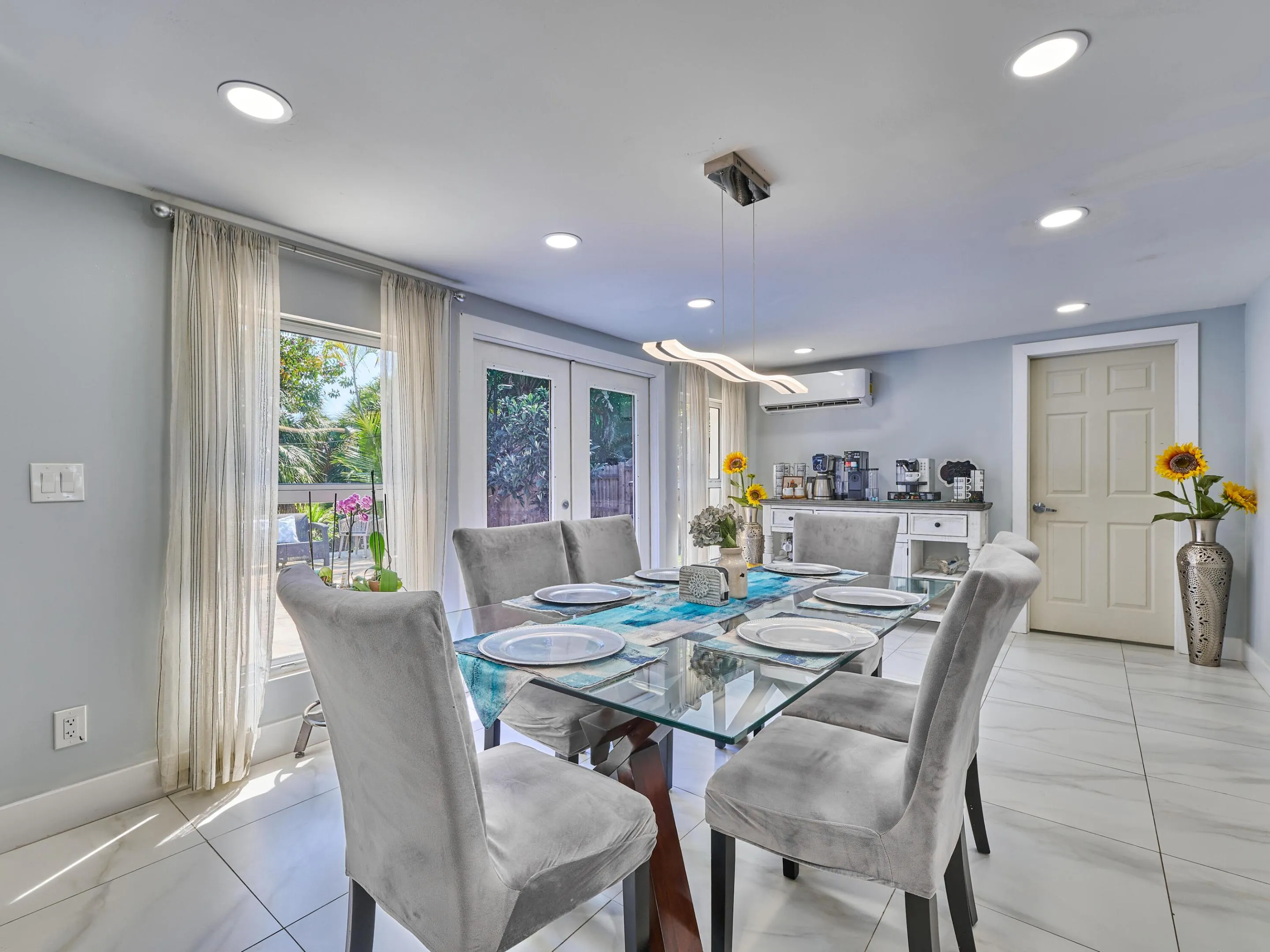 Recessed ceiling lighting, glass-panel French doors, light-toned wall paint, white tile flooring, and a contemporary linear pendant light fixture