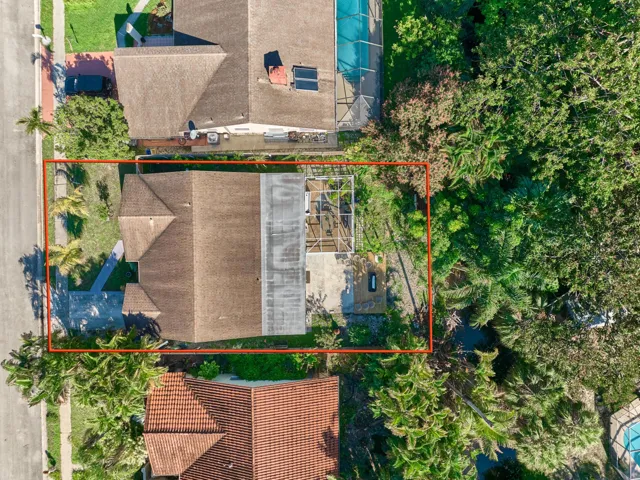 Gable roofline residence with a driveway, mature landscaping, and a screened outdoor structure