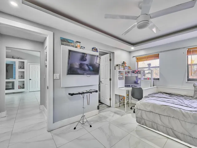 White tile flooring, tray ceiling, recessed lighting, ceiling fan, and built-in shelving