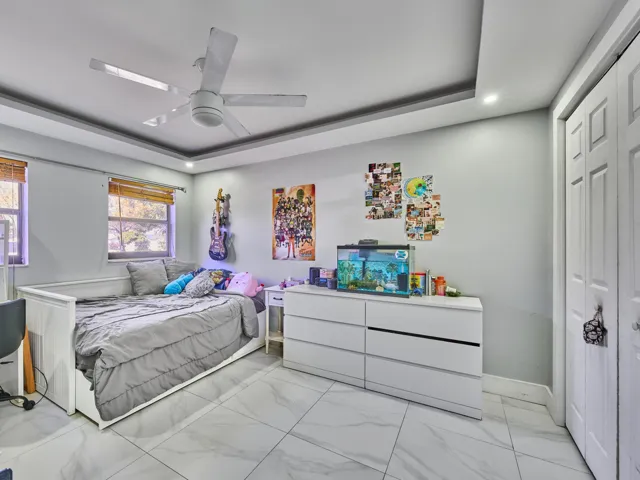 Recessed lighting, tray ceiling, tile flooring, window with blinds, and bifold closet doors