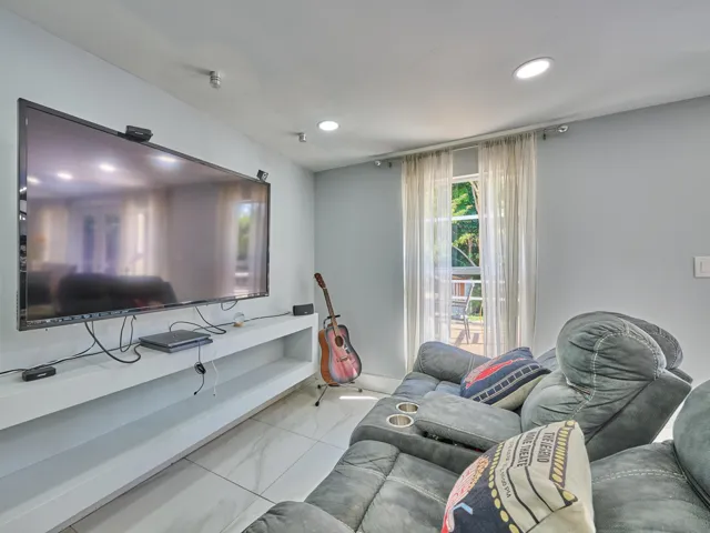 Recessed ceiling lighting, a large built-in media shelf, and tile flooring