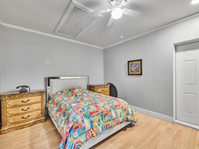 Bright secondary bedroom featuring wood-finish flooring, soft neutral wall finishes, and a ceiling fan with integrated lighting