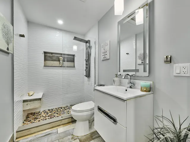 Walk-in shower with textured tile surround and pebble floor