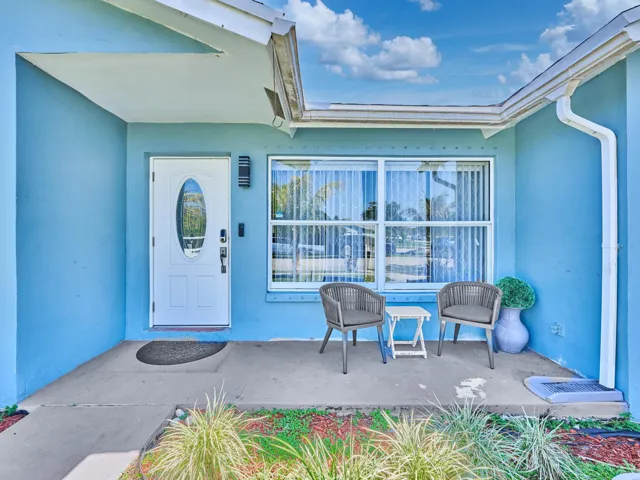 Front entry with a white oval-lite door, covered concrete porch, and a large multi-pane window