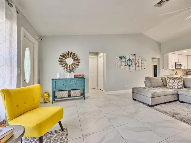 Vaulted ceiling, white tile flooring, recessed lighting, white wall finishes, and a kitchen pass-through