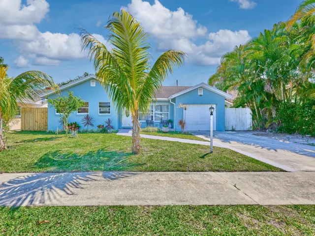 Front exterior with blue siding, a white garage door, and a concrete driveway