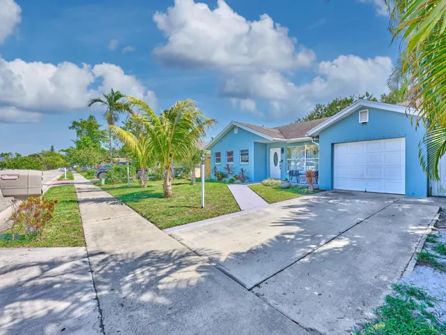 Single-story residence featuring a blue exterior, a covered entryway, a white garage door, and a concrete driveway