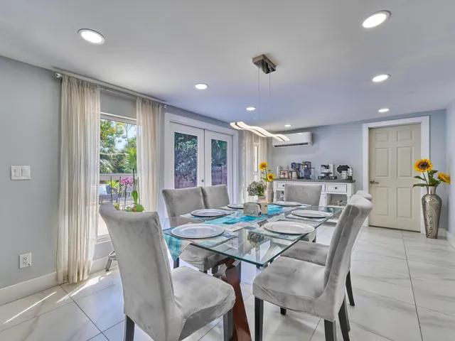 Recessed ceiling lighting, glass-panel French doors, light-toned wall paint, white tile flooring, and a contemporary linear pendant light fixture