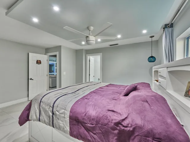 Recessed lighting, ceiling fan, tray ceiling, built-in shelving, and tile flooring