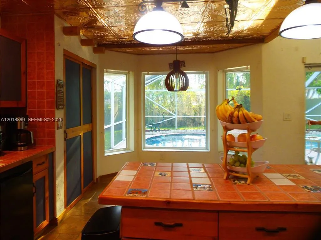 Kitchen featuring a tiled accent wall, custom wood cabinetry, and a textured ceiling