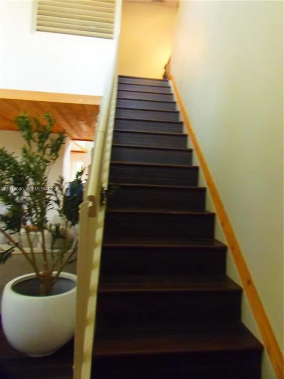 Staircase with dark wood-finish treads and risers, light-toned wood handrail, and white wall finishes