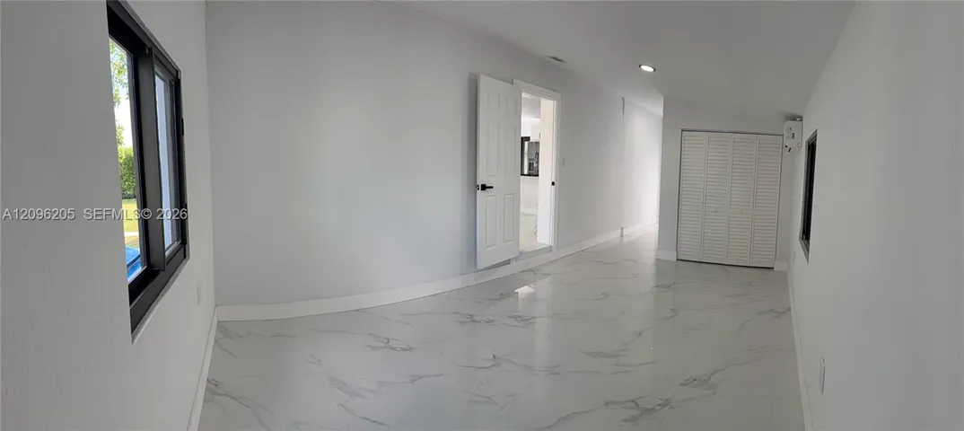 Interior space featuring polished stone-finish tile flooring, recessed ceiling lighting, a closet with white louvered doors, and a six-panel interior door