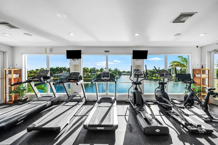 Fitness center with floor-to-ceiling windows, recessed lighting, and water scenery