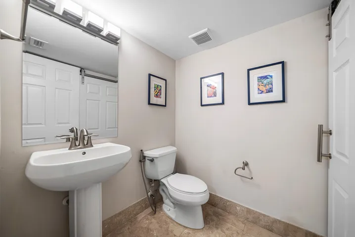 Pedestal sink with brushed nickel faucet, mirror with overhead lighting, large storage closet and barn door