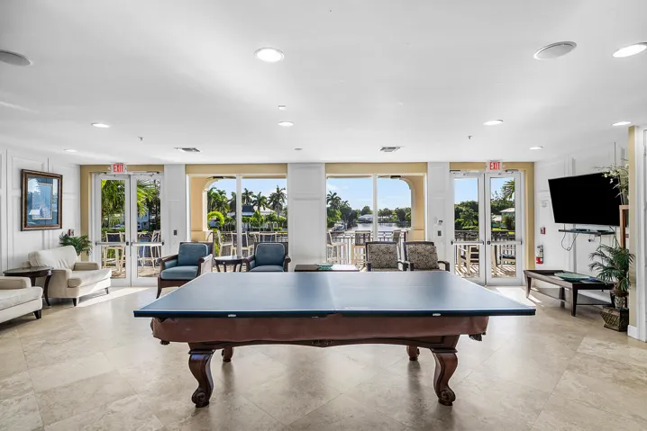 Expansive recreational space featuring a billiards table, recessed lighting, and direct access to an outdoor patio with water frontage