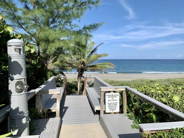 Beachfront access with a wooden boardwalk, mature palm trees, and ocean scenery