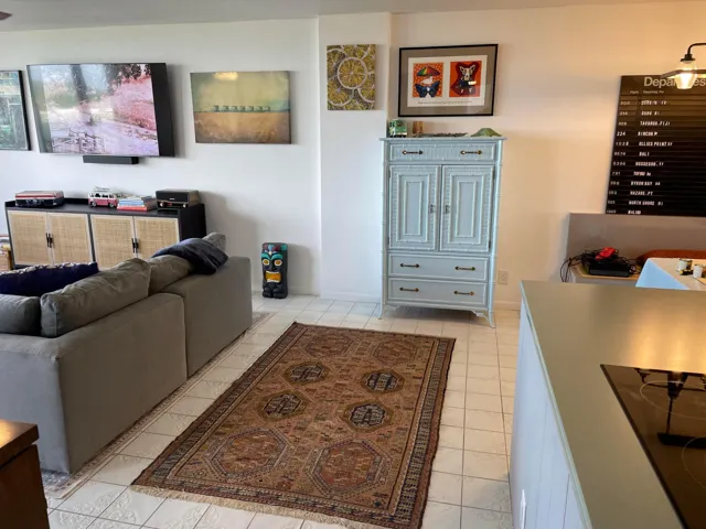 White tiled flooring, built-in media console with woven doors, light blue painted cabinet with drawers, white walls, and a mounted display board