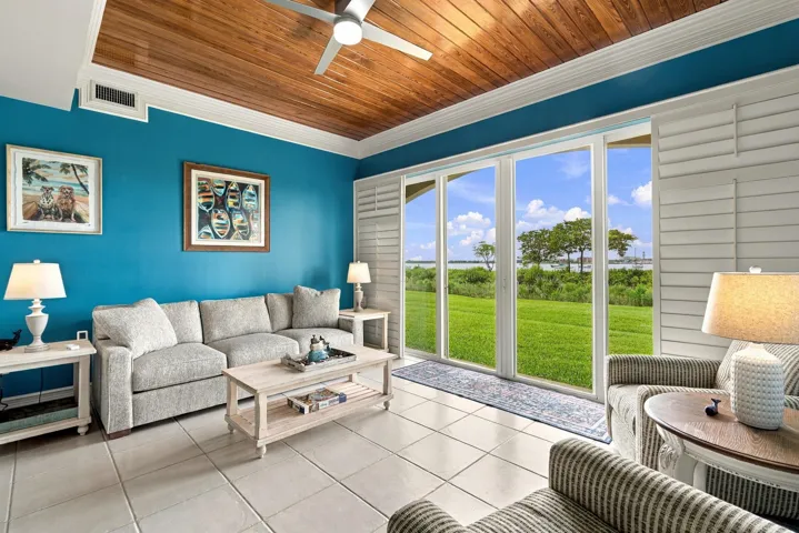 Sunroom has a warm, beachy feel and has a bead board ceiling and plantation sliders.