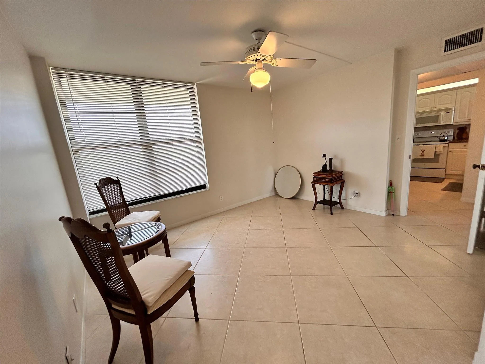 Tile flooring, ceiling fan with integrated lighting, and a large window with blinds