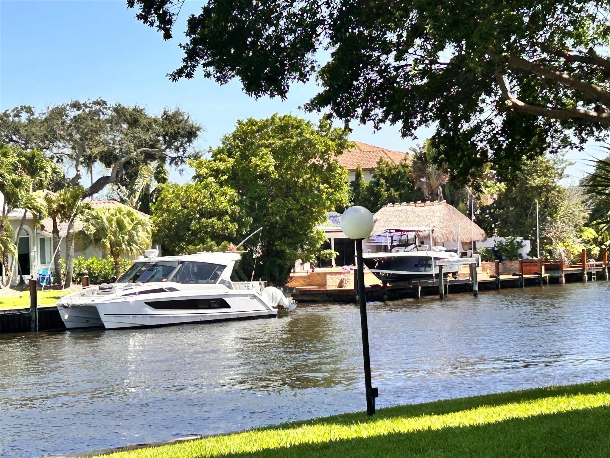 Waterfront property featuring a canal, private boat dock, and lush mature trees
