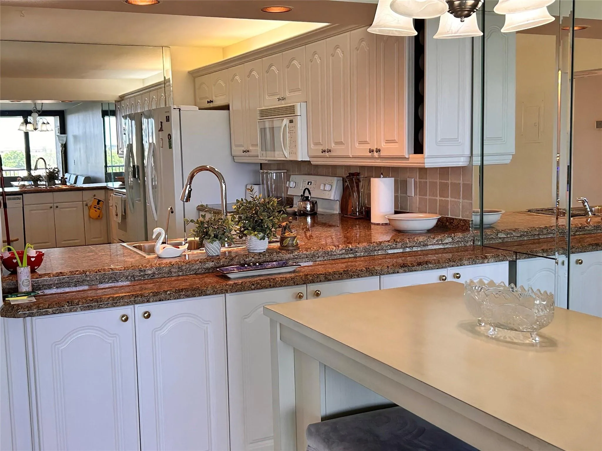 Kitchen featuring white cabinetry, granite countertops, tile backsplash, and a stainless steel sink with a high-arch faucet