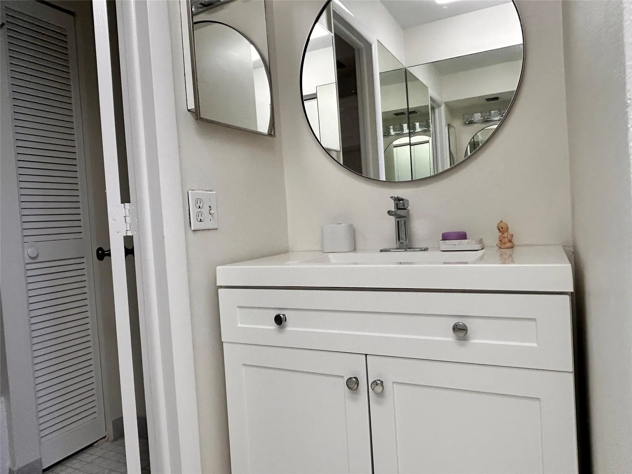 White vanity with a single basin sink, chrome faucet, and integrated countertop