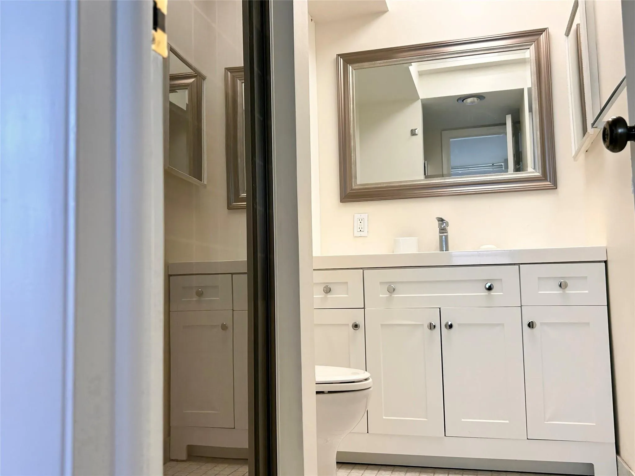 White vanity with cabinetry and drawers, integrated rectangular sink, framed mirror, and chrome faucet