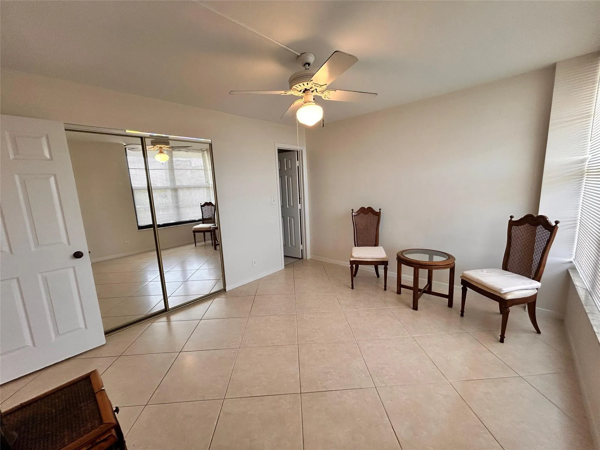 Tile flooring, mirrored closet doors, ceiling fan with integrated lighting, and window blinds