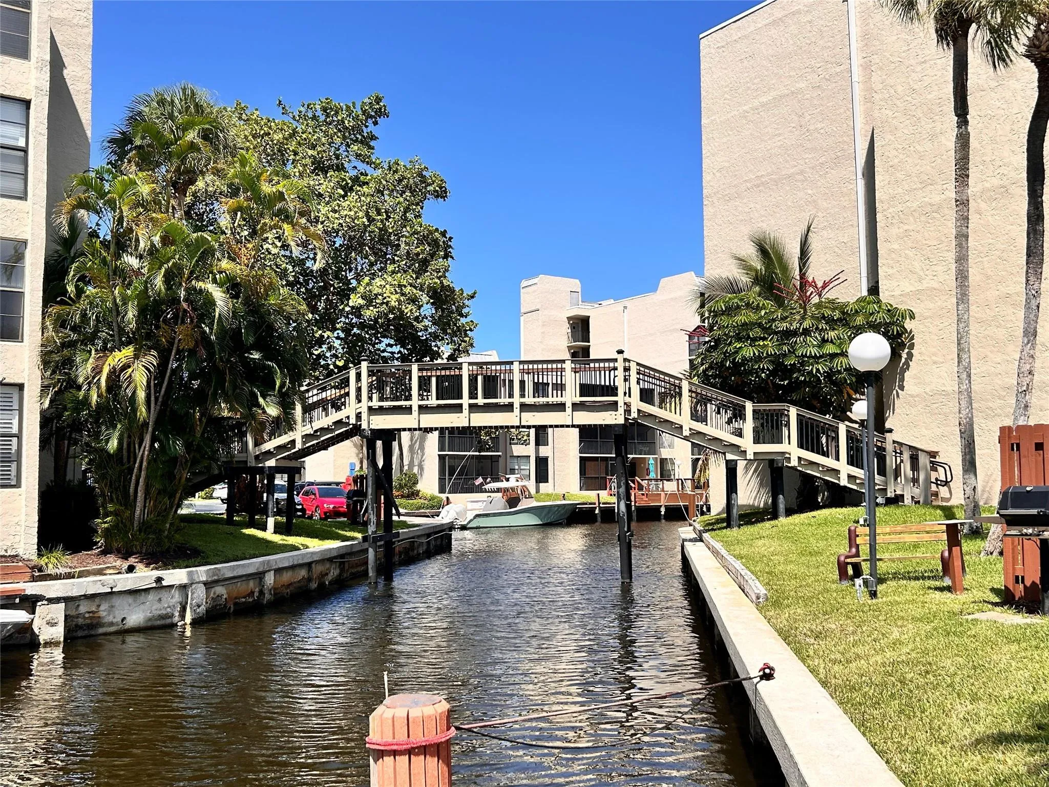 Waterfront property with a pedestrian bridge, concrete seawall, and mature tropical landscaping
