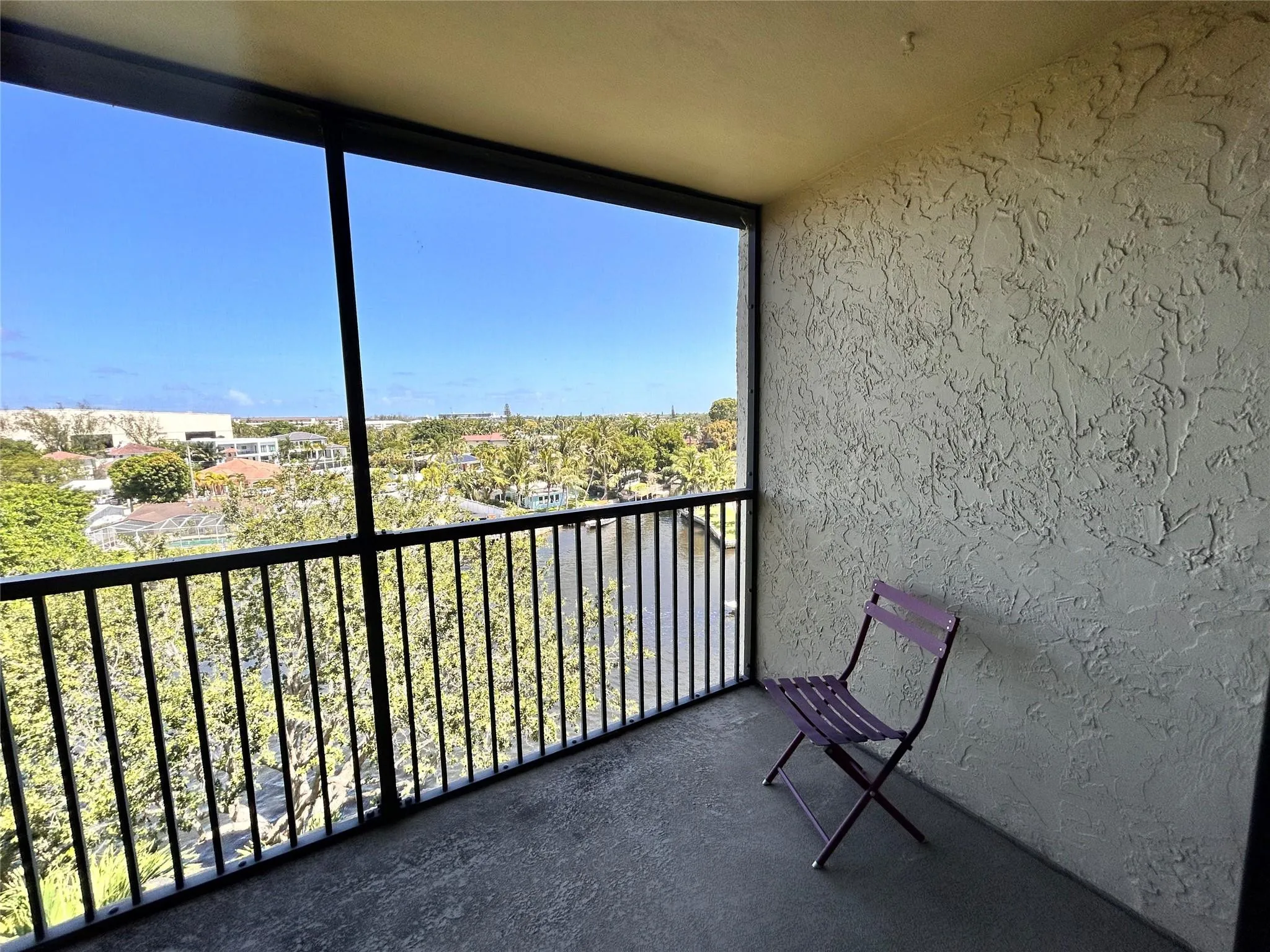 Screened balcony featuring a textured wall finish and a metal railing