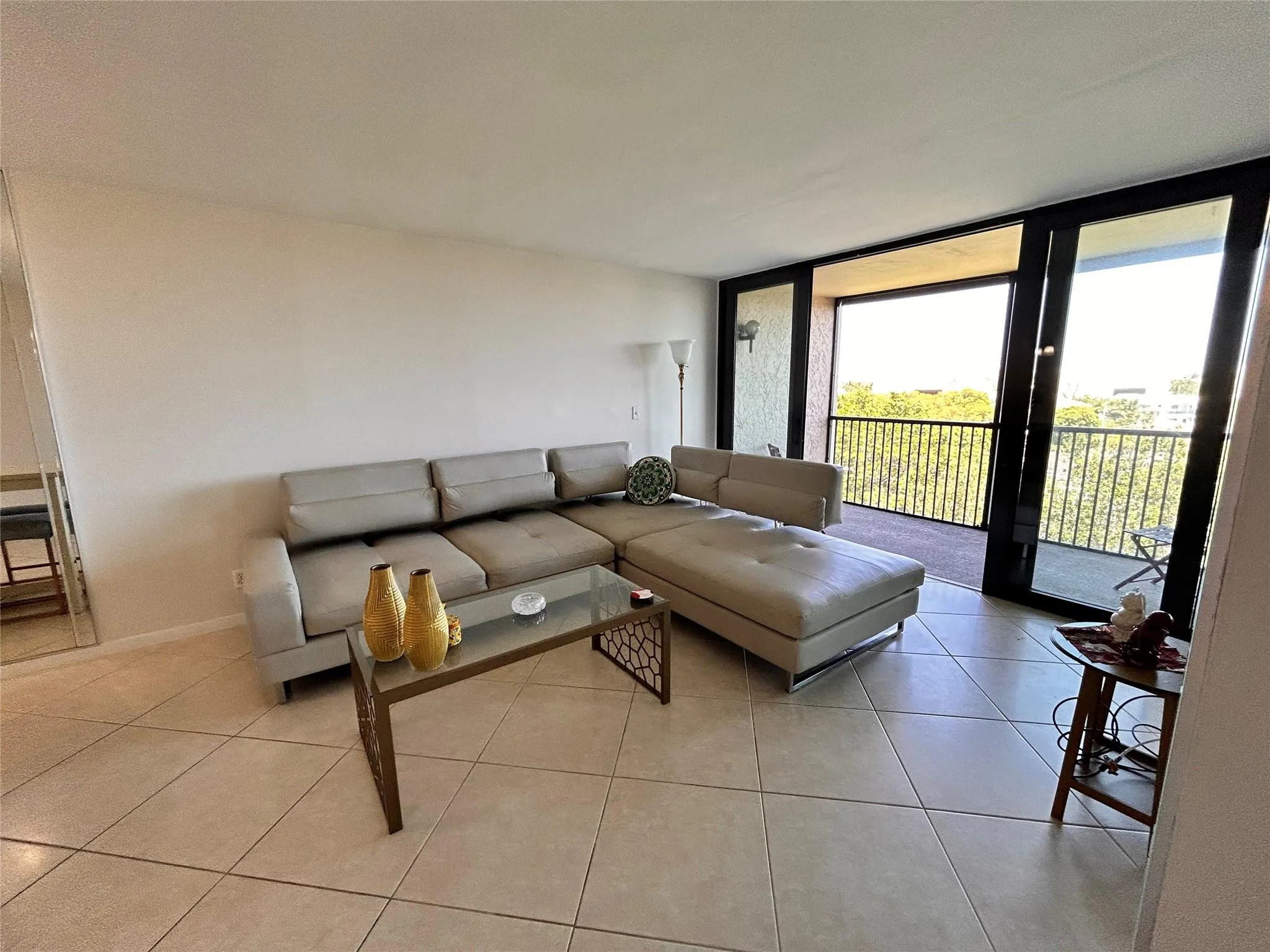 Expansive room featuring light-toned tile flooring, direct balcony access, and full-height glass doors