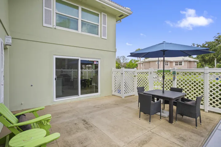 Private patio space featuring a concrete surface, lattice fencing, and sliding glass doors
