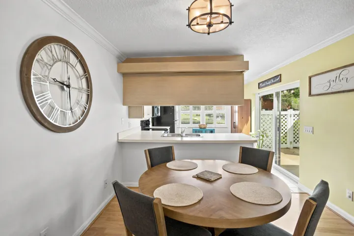 Dining area with wood-finish flooring, crown molding, and a built-in pass-through counter