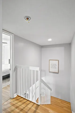 Hardwood flooring leading to a white wood baluster staircase