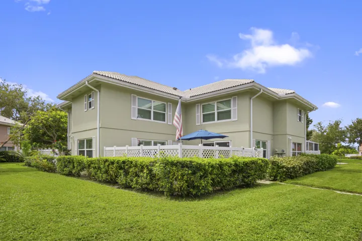 Two-story exterior with a light-colored stucco finish, white window shutters, and a tiled roof