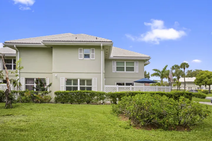 Two-story exterior with a tile roof, white shutters, and a rear patio featuring a white lattice fence