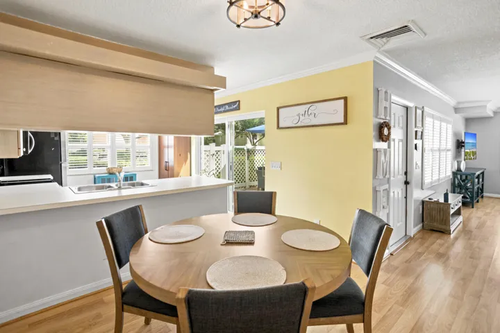 Open concept dining area with wood-finish flooring, featuring a built-in breakfast bar with a solid surface countertop, and a sliding glass door