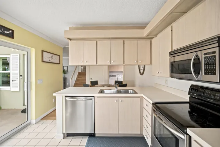 Kitchen featuring light-toned cabinetry, stainless steel dishwasher, built-in microwave, and a stainless steel sink