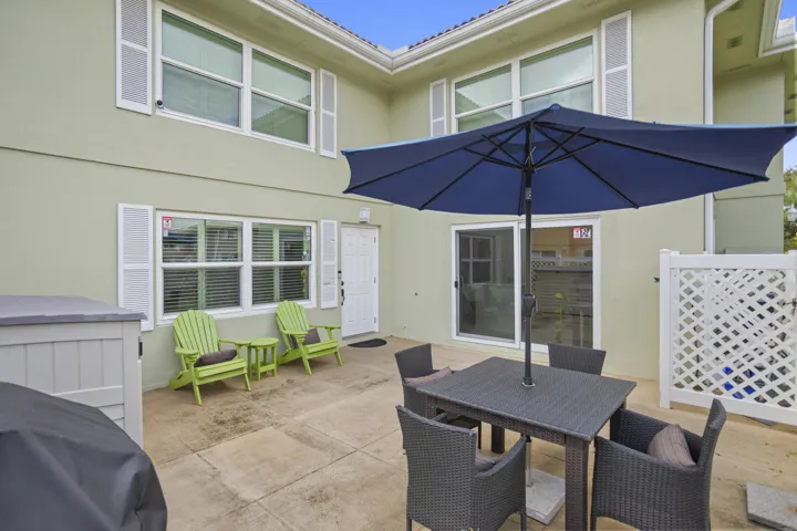 Expansive patio featuring a concrete surface, white lattice fencing, and a sliding glass door