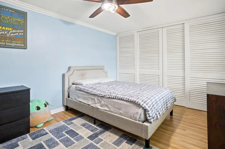 Wood-finish flooring throughout, crown molding, and a ceiling fan