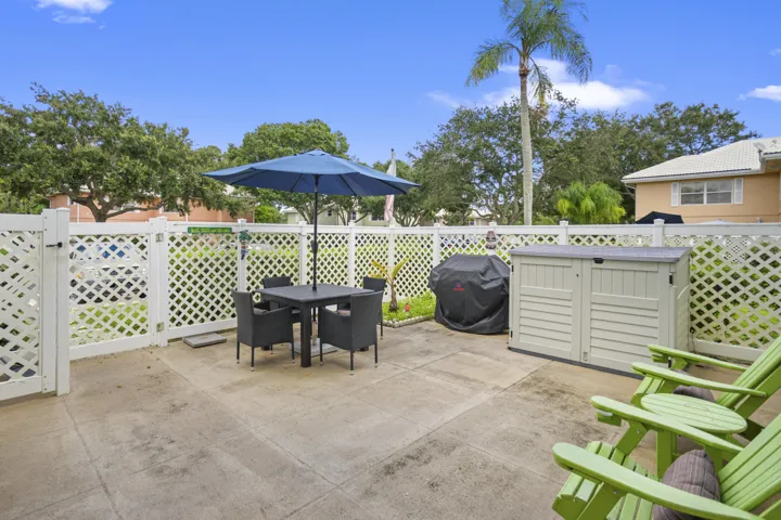 Outdoor patio with concrete flooring, white lattice fencing, and a built-in storage shed