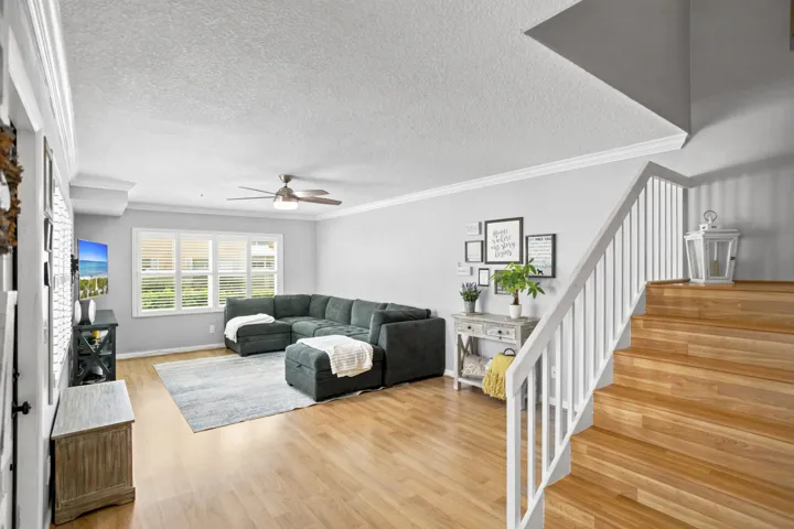 Hardwood flooring, white window shutters, white crown molding, and white painted balusters