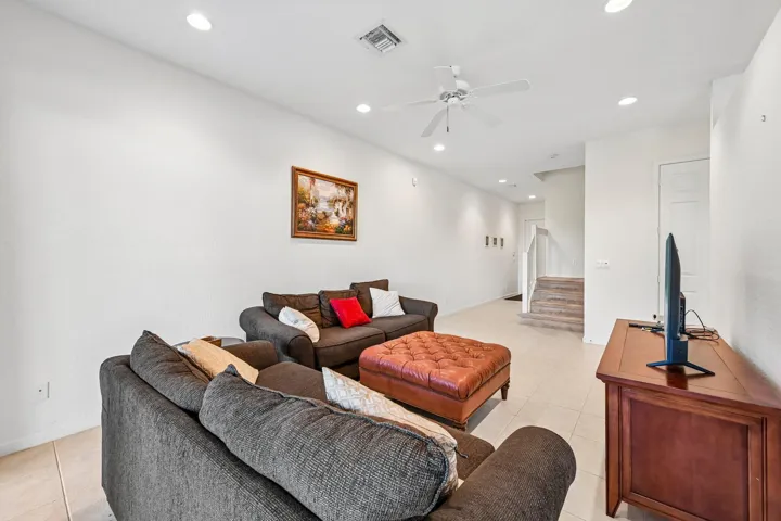 Recessed lighting, ceiling fan, neutral wall paint, tiled flooring, and a stairway with carpeted treads