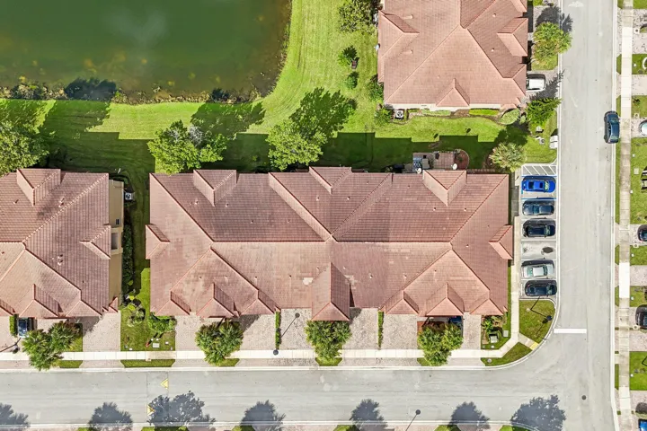 Tile roof residences with adjacent paved parking areas and a manicured green space bordering a body of water
