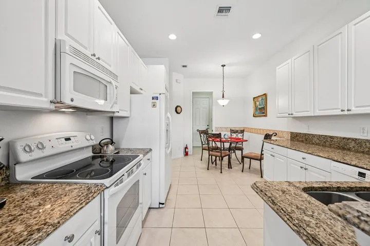 Kitchen featuring white cabinetry, light-toned granite countertops, white appliances, and tiled flooring