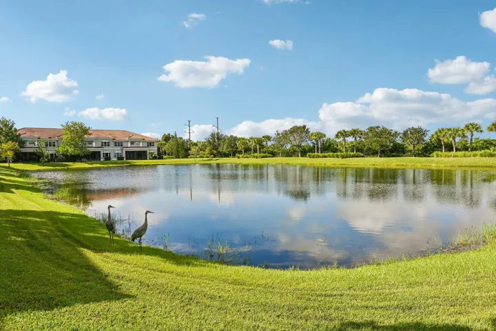 Expansive waterfront property with a manicured lawn, mature trees, and a multi-level residential building