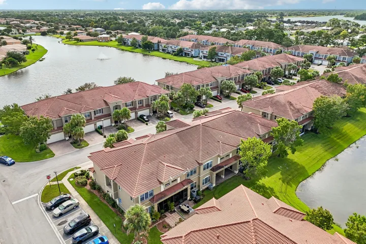 Aerial overview showcasing multiple two-story properties with tile roofs, an integrated parking area, and mature landscaping