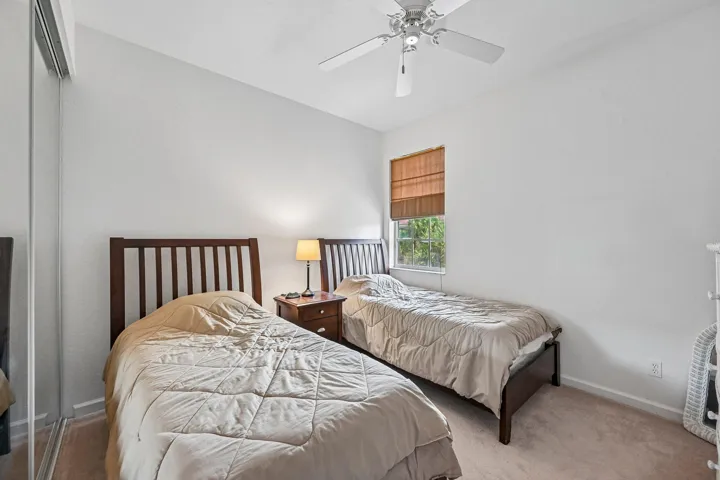 Ceiling fan with light fixture, window with woven shade, and carpet flooring