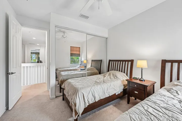 Wall-to-wall carpeting with mirrored closet doors, a ceiling fan, and a paneled interior door